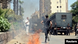 Police take positions after a protest was dispersed quickly, leaving fire burning in a main street in Giza, south of Cairo, August 14, 2014. 