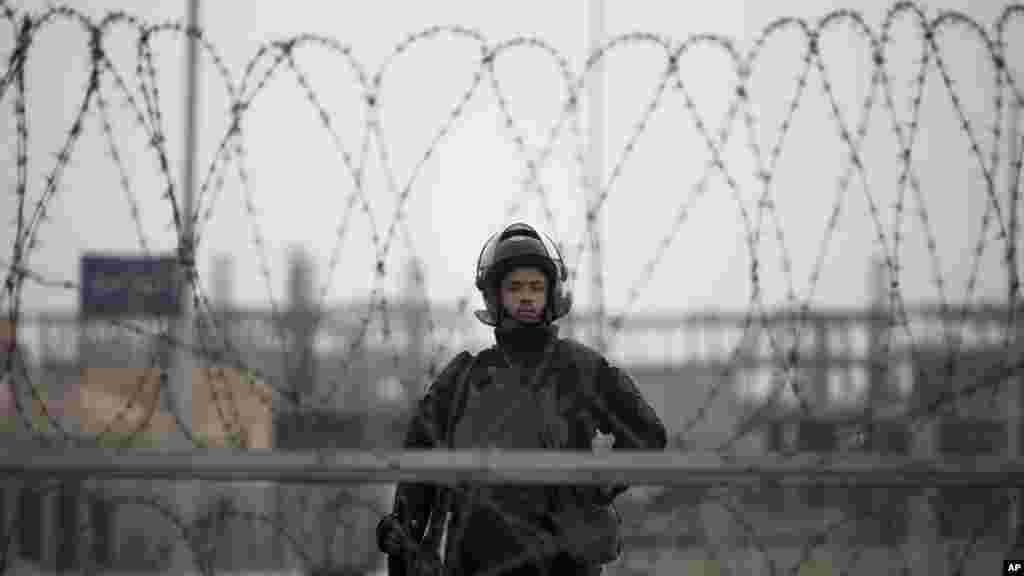 A riot policeman stands guard behind barbed wire outside of a police academy compound where the trial of ousted President Mohammed Morsi is being held, Cairo, Egypt. 