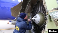 A U.S. NTSB investigator is shown examining damage to the engine of the Southwest Airlines plane in this image released from Philadelphia, April 17, 2018. 