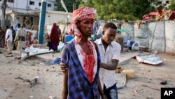 A Somali helps an injured civilian who was wounded in a bomb blast near the Sahafi hotel in the capital Mogadishu, Somalia, Nov. 9, 2018.