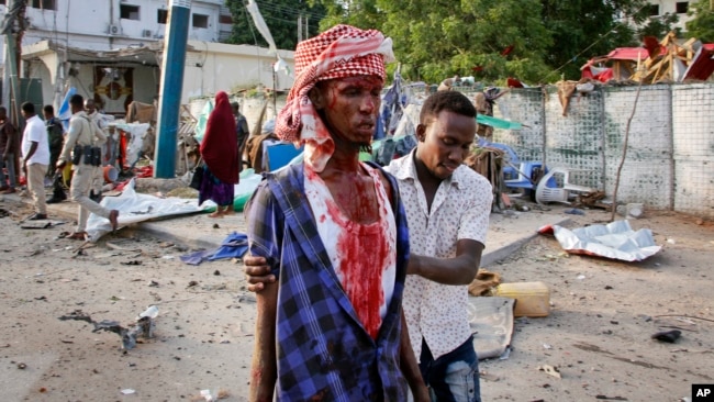 A Somali helps an injured civilian who was wounded in a bomb blast near the Sahafi hotel in the capital Mogadishu, Somalia, Nov. 9, 2018.