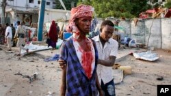 A Somali helps an injured civilian who was wounded in a bomb blast near the Sahafi hotel in the capital Mogadishu, Somalia, Nov. 9, 2018.