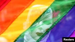 FILE - A participant stands behind a rainbow flag during a gay pride parade promoting lesbian, gay, bisexual and transgender rights, in Chennai, India, June 24, 2018.