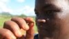 A woman holds an army worm she found feeding on her maize crop at a Farm on the outskirts of Harare, Zimbabwe, Feb. 14, 2017.