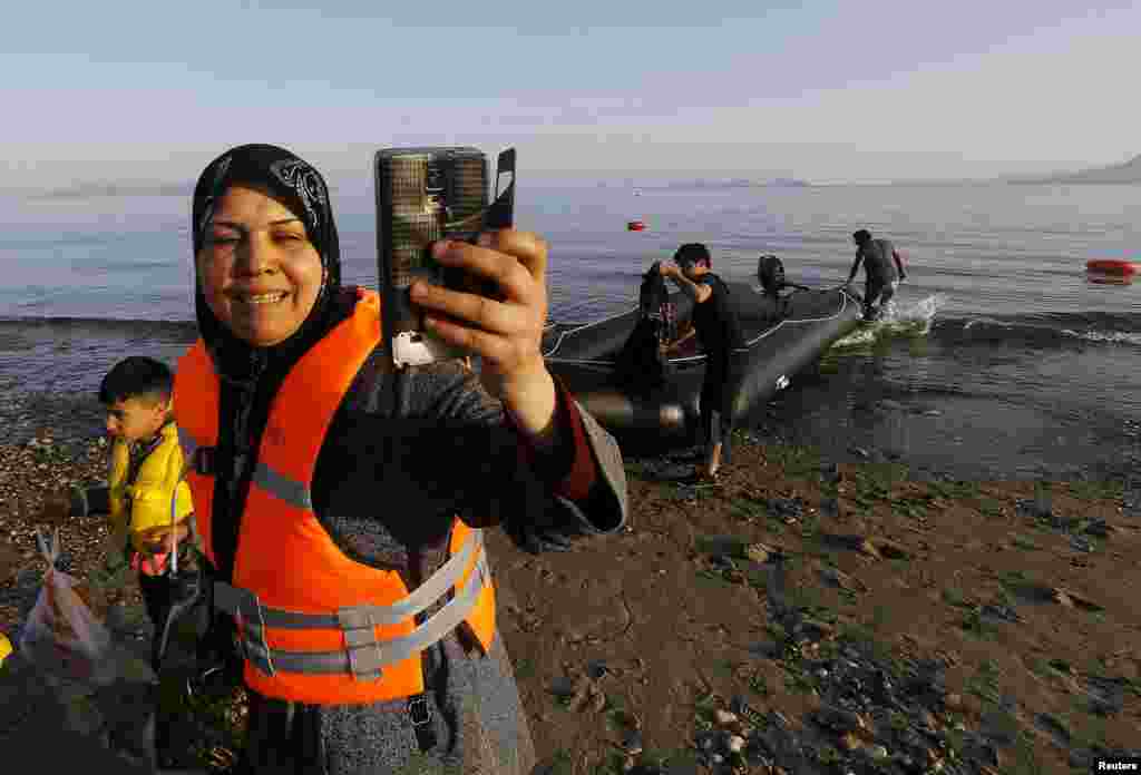 A Syrian refugee woman talks a 'selfie' picture as she walks on the beach after arriving on the Greek island of Kos with her family on a dinghy boat, after crossing part of the Aegean Sea from Turkey to Greece, May 26, 2015.