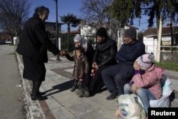 A local (L) offers migrants who are making their way to the Greek-Macedonian border something to eat, at the Greek village of Idomeni, Greece, March 5, 2016.