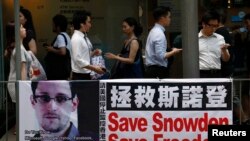 Des passants accrochés à leurs téléphones portables se succédant devant une banderole en soutien à Edward Snowden, ex-consultant de la National Security Agency (NSA), dans le centre financier de Hong Kong, 18 juin 2013.