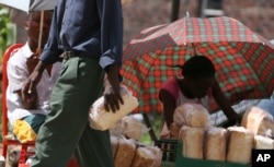 A man holds a loaf of bread after buying it from a black market dealer who accepted 15 million Zimbabwean dollars Wednesday March 26 2008.