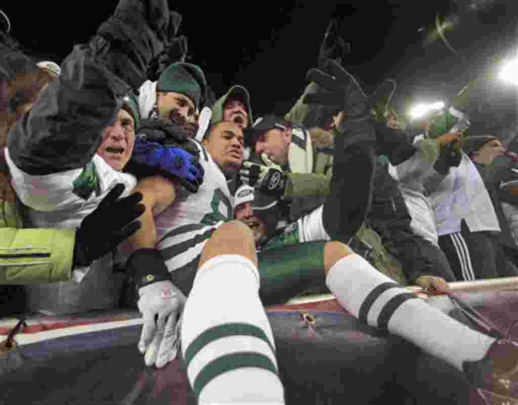 Dustin Keller, de los New York Jets, celebra con los fans la victoria de su equipo que dejó eliminados a los New England Patriots.