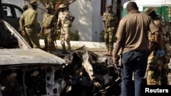 Nigerian bomb experts and military personnel investigate the site of an explosion at a police station in Kano, Nov. 15, 2014.