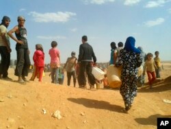 FILE - Syrian refugees gather for water at the Rukban camp for displaced Syrians, on the Jordan and Syria borders, June 23, 2016.