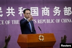 FILE - Chinese Ministry of Commerce spokesman Gao Feng gestures as journalists raise hands for questions during a press conference at the Ministry of Commerce in Beijing, April 6, 2018.