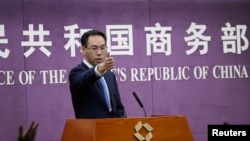 FILE - Chinese Ministry of Commerce spokesman Gao Feng gestures as journalists raise hands for questions during a press conference at the Ministry of Commerce in Beijing, April 6, 2018. 