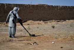 FILE - A deminer from the HALO (Hazardous Area Life-Support Organization) Trust scanning the ground for mines with a metal detector in Nad-e-Ali village in Helmand province, Nov. 9, 2021.