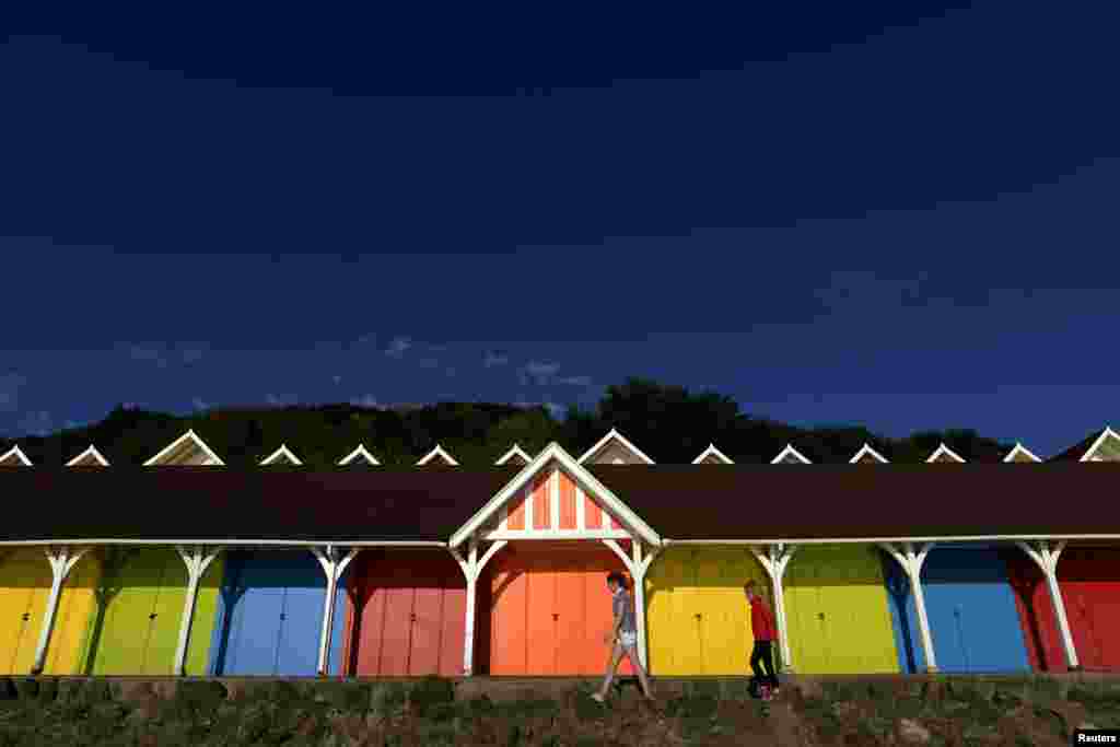 Two girls walk past beach huts in the North Bay in Scarborough, northern England. The Grade 11 listed structures on the North Bay were introduced in 1911 and are still used today. 