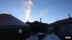 "Chimneys" fume in the camp from wood stove heaters set up in long-term tents. (E. Sarai/VOA)