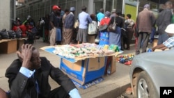 FILE: In this Tuesday, Dec. 20, 2016 photo, a man takes time to sit down after waiting for hours in a bank queue in Harare. (AP Photo/Tsvangirayi Mukwazhi)