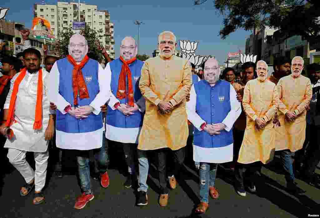 Supporter of India&#39;s ruling Bharatiya Janata Party (BJP) wearing cut-outs of Prime Minister Narendra Modi and the party president Amit Shah walk during an election campaign in Ahmedabad.