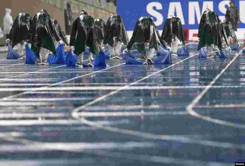 인천 아시안게임 주경기장에서 남녀 100미터 달리기 결승전을 앞두고 소나기가 내린 가운데, 진행 요원들이 트랙 위의 물기를 닦아내고 있다. 