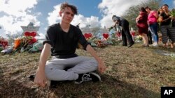 Chris Grady, un estudiante de la escuela secundaria Marjory Stoneman Douglas, posa frente a un monumento en honor de las víctimas de la matanza de la semana pasada en Parkland, Florida.