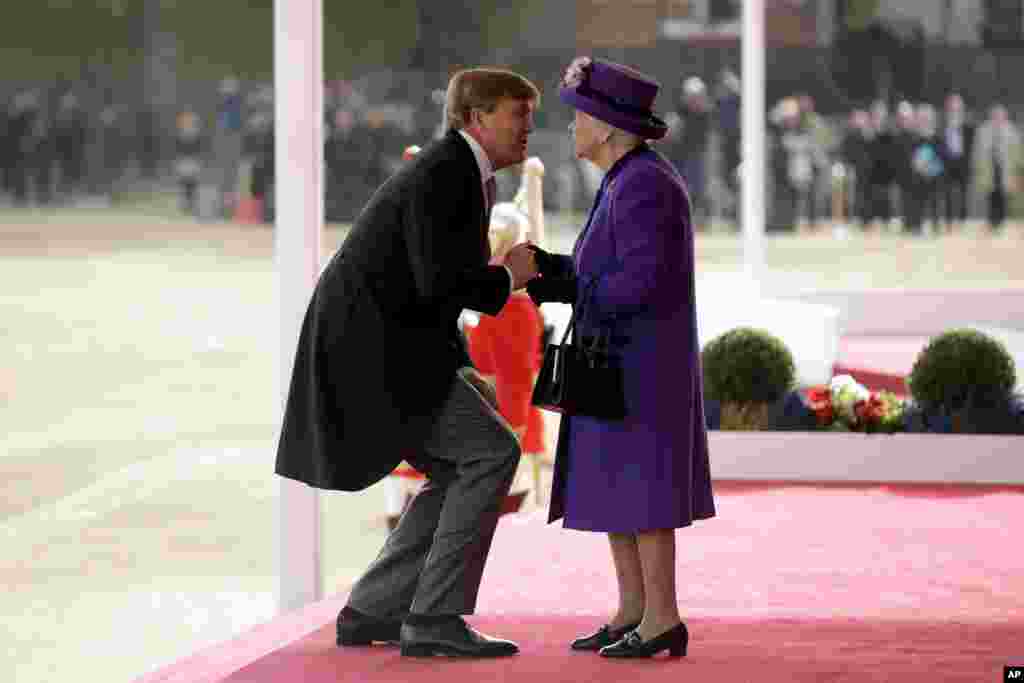 Netherlands&#39; King Willem-Alexander bends down to kiss Britain&#39;s Queen Elizabeth II as she greets him upon his arrival during a Ceremonial Welcome on Horse Guards Parade in London, Oct. 23, 2018.