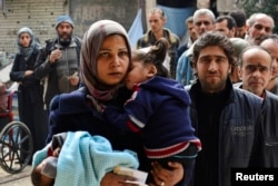 FILE - Residents line up to receive humanitarian aid at the Palestinian refugee camp of Yarmouk, in Damascus, Syria, March 11, 2015.