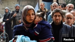 FILE - Residents line up to receive humanitarian aid at the Palestinian refugee camp of Yarmouk, in Damascus, Syria, March 11, 2015. 