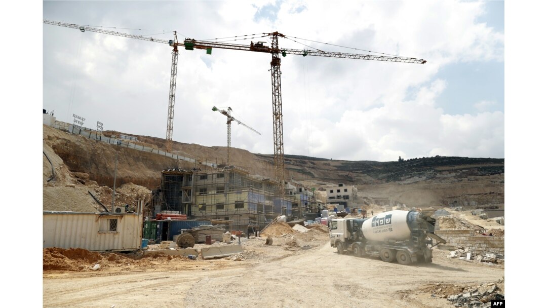 FILE - Workers and bulldozers are seen at a construction site in the Israeli settlement of Givat Zeev near the West Bank city of Ramallah, April 14, 2016.