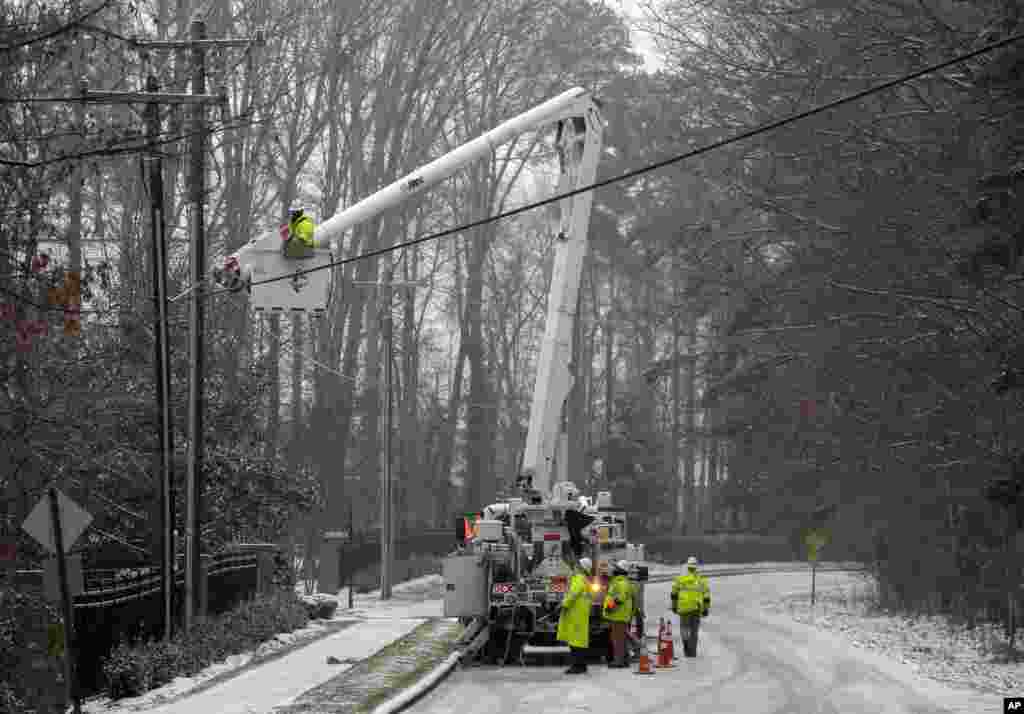 Duke Energy employees work to restore power in a neighborhood in Matthews, North Carolina, Jan. 22, 2016.