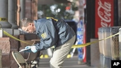An FBI agent writes down information as he looks at a chair and the ground where Rep. Gabrielle Giffords was shot at a local Safeway in Tucson, Arizona, 10 Jan 2011