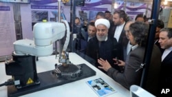 In this photo released by an official website of the office of the Iranian Presidency, President Hassan Rouhani listens to explanations on new nuclear achievements at a ceremony to mark "National Nuclear Day," in Tehran, Iran, April 9, 2018.