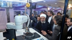 FILE - In this photo released by an official website of the office of the Iranian Presidency, President Hassan Rouhani listens to explanations on new nuclear achievements at a ceremony to mark "National Nuclear Day," in Tehran, Iran, April 9, 2018.