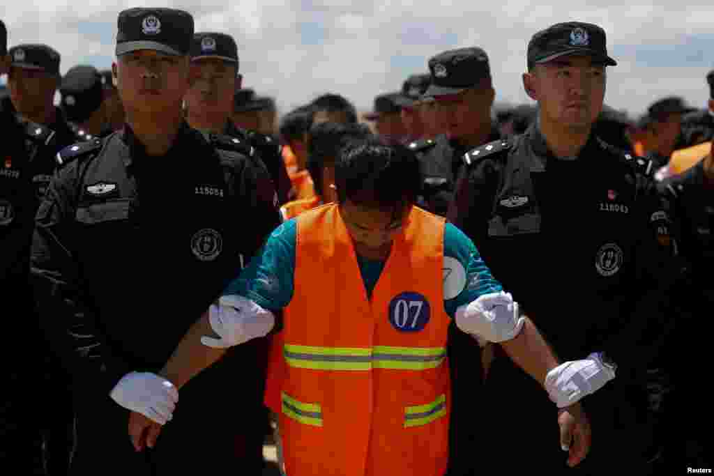 Chinese nationals (in orange vests) who were arrested over a suspected internet scam, are escorted by Chinese police officers before they were deported at Phnom Penh International Airport, in Phnom Penh, Cambodia, Oct.