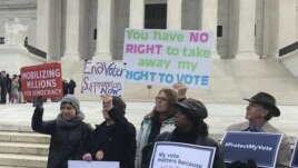 FILE - Activists rally outside the U.S. Supreme Court ahead of arguments in a key voting rights case involving a challenge to Ohio's policy of purging infrequent voters from voter registration rolls, in Washington, Jan. 10, 2018.