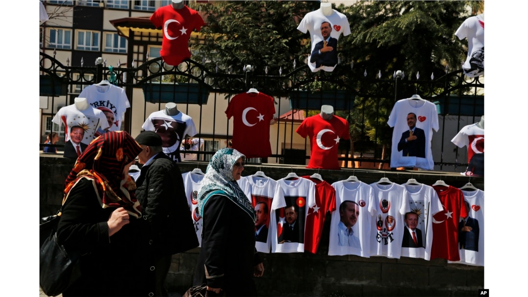 People walk past a display of T-shirts adorned with images of the Turkish flag and President Recep Tayyip Erdogan, offered for sale in his hometown city of Rize, April 4, 2017, ahead of an April 16 referendum on extending presidential powers.