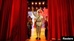 An actor dressed as an Eighth Route Army soldier waves after a performance at the Eighth Route Army Culture Park, one of two theme parks, in Wuxiang county, north China's Shanxi province, October 20, 2012. 
