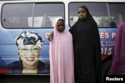 FILE – Girls pose near a vehicle bearing an image of Aisha Jummai Alhassan, the northeastern Taraba state candidate who would be Nigeria’s first female governor, in Jalingo city, April 10, 2015.