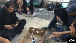 Outside Vienna train station, aid workers provide what many refugees want most: electricity to charge mobile phones that kept them alive and on track so far, Sept. 15, 2015. (H. Murdock / VOA) 