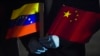 FILE - In this March 30, 2020, photo, Venezuela's Foreign Minister Jorge Arreaza holds Venezuelan and Chinese flags as medical specialists and supplies arrive from China at the Simon Bolivar International Airport in La Guaira, Venezuela.