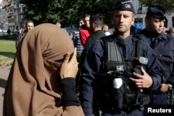 Seorang perempuan bercadar, menutupi matanya saat dia berdiri di dekat polisi saat pemeriksaan identitas ketika dia tiba untuk berdemonstrasiuntuk memprotes video anti-Islam, di Lille 22 September , 2012. (Foto: REUTERS/Pascal Rossignol)