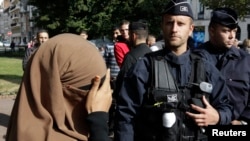 Une femme porte un voile intégral, ou niqab, et couvre ses yeux à l'approche de la police à Lille, France, le 22 septembre 2012.