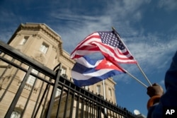 Edwardo Clark, a Cuban-American, holds an American flag and a Cuban flag as he celebrates outside the new Cuban embassy in Washington, July 20, 2015.