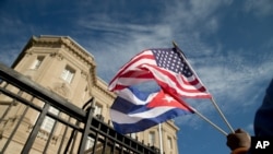 一名古巴裔美国人在古巴驻华盛顿新开使馆前挥舞两国国旗庆祝 (2015年7月21日)。