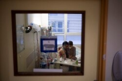 Amelie and Ludo Khayat hold each other during a visit at the COVID-19 intensive care unit of the la Timone hospital in Marseille, southern France, Thursday, Dec. 23, 2021.