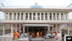 Les employés municipaux afghans balaient devant la mosquée Baqir-ul Ulom après une attaque, à Kaboul, Afghanistan, le 21 novembre 2016.