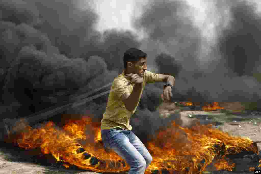 A Palestinian slings a shot by burning tires during clashes with Israeli forces across the border, following a demonstration calling for the right to return to Israel, in Gaza City.