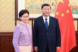 In this photo released by Xinhua News Agency, Chinese President Xi Jinping, right, poses for a photo with Chief Executive of the Hong Kong Special Administrative Region Carrie Lam, during their meeting in Beijing, China, Dec. 22, 2021.