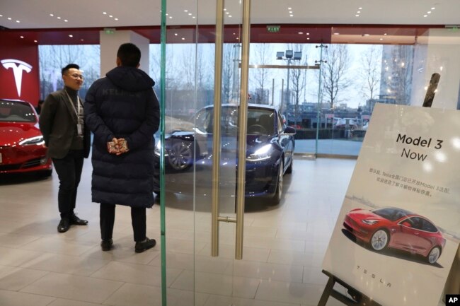 Un vendedor habla con un cliente en una tienda de Tesla en Beijing, China, el lunes, 7 de enero de 2019.