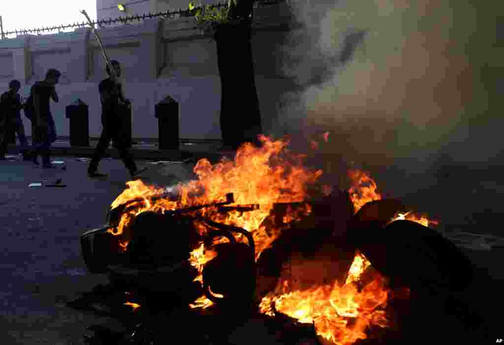 Opponents of ousted President Mohammed Morsi hold sticks and pass past a burning scooter, that was set on fire during clashes with Morsi supporters, in Cairo, Egypt, July 22, 2013.