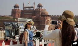 Visitors take photos in front of a 1909 Rolls Royce Silver Ghost displayed at the 6th 21 Gun Salute International Vintage Car Rally & Concours Show in New Delhi, India. Seen behind is the Red Fort monument.